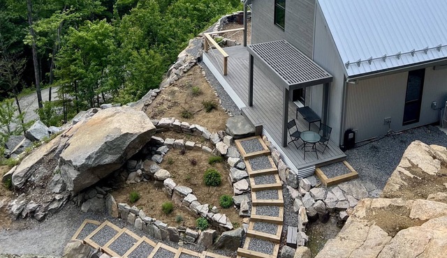 Designer cabin perched above valley, boasts stunning panoramic views.